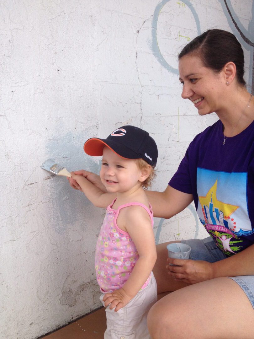 A woman is painting a wall with a brush.