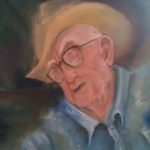 A man in a hat wearing glasses painting