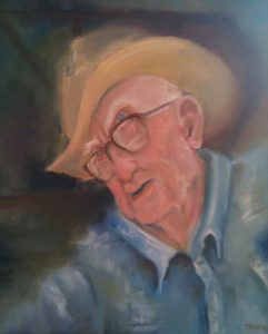 A man in a hat wearing glasses painting