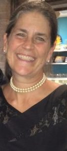 Smiling woman wearing pearl necklace indoors.