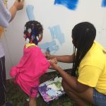 A kid and a woman painting a wall