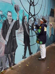 A woman in a black jacket painting a wall