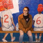 A girl sitting in front of a wall painting