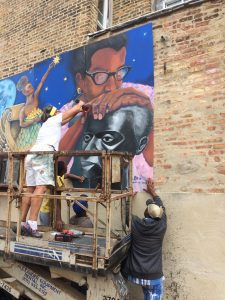 A woman and a man working on a wall painting