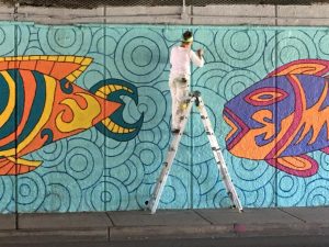 A woman standing on a ladder painting a wall