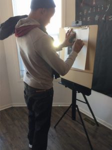 A boy sketching with a canvas stand