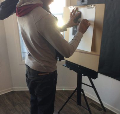 A boy sketching with a canvas stand