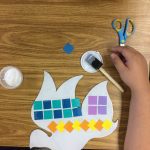 A kid making a colorful paper bird