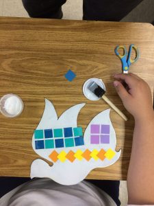 A kid making a colorful paper bird