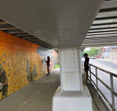 A woman painting a wall and a woman watching her