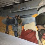 Painting of men and a fighter plane on the wall