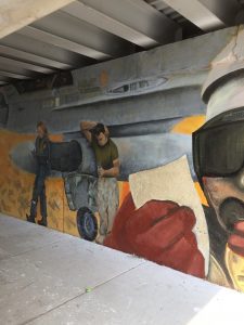 Painting of men and a fighter plane on the wall