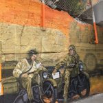 Painting of two men on a bike