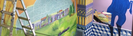 A mural is being painted on the wall of a building.