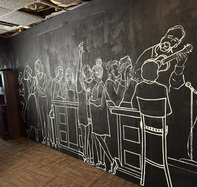 A blackboard with a drawing of people in a room.