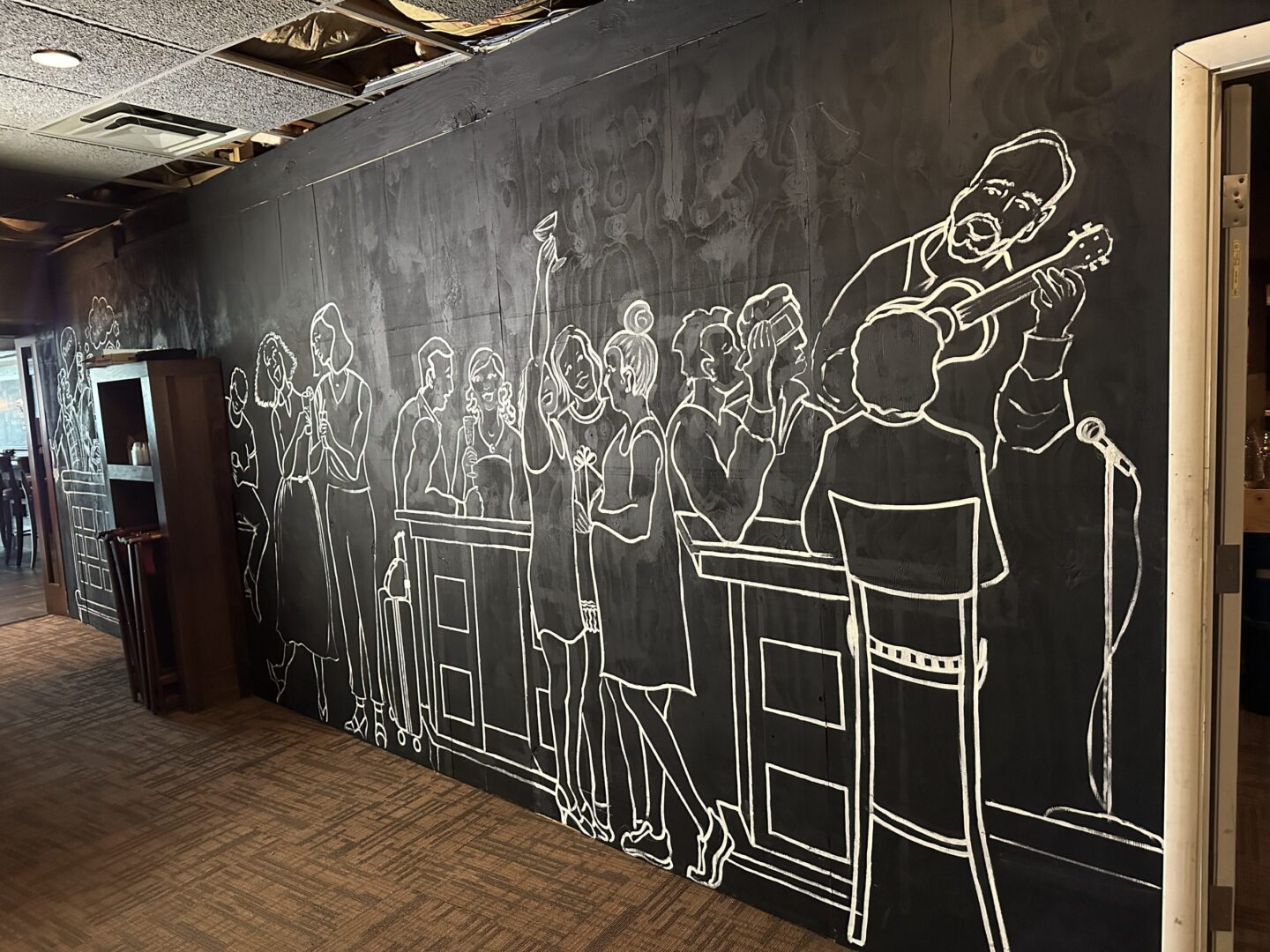 A blackboard with a drawing of people in a room.