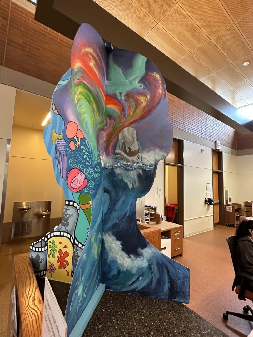 A mural of a woman sitting at a desk in a library.