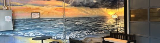 Cozy lounge with ocean mural and seating.