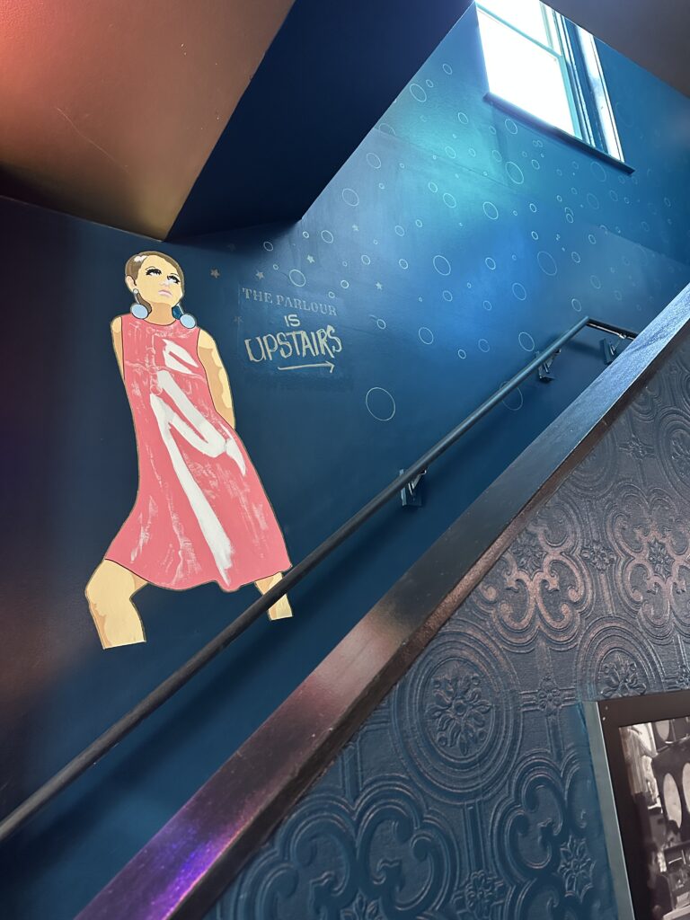 Staircase mural of woman in pink dress.